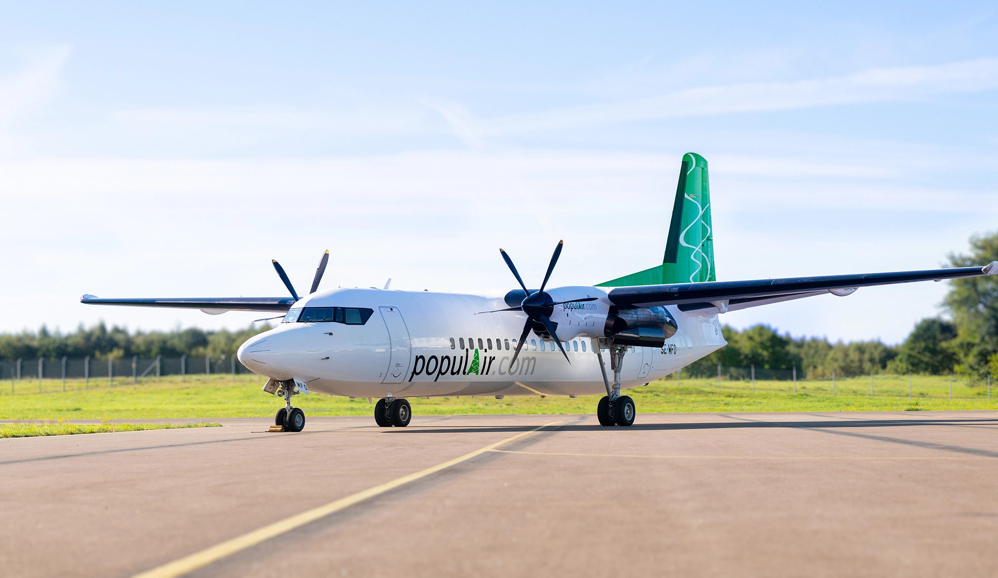 Fokker 50 - ett vitt flygplan med grön akterfena under en blå himmel